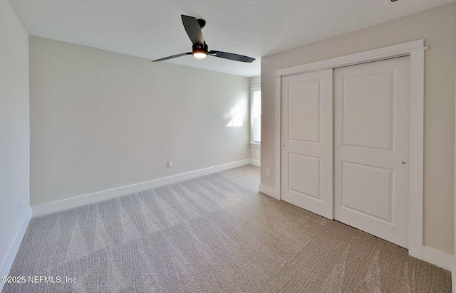 unfurnished bedroom featuring carpet floors, a closet, ceiling fan, a textured ceiling, and baseboards