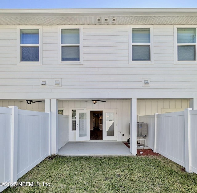 back of property featuring board and batten siding, a patio area, fence, and a lawn