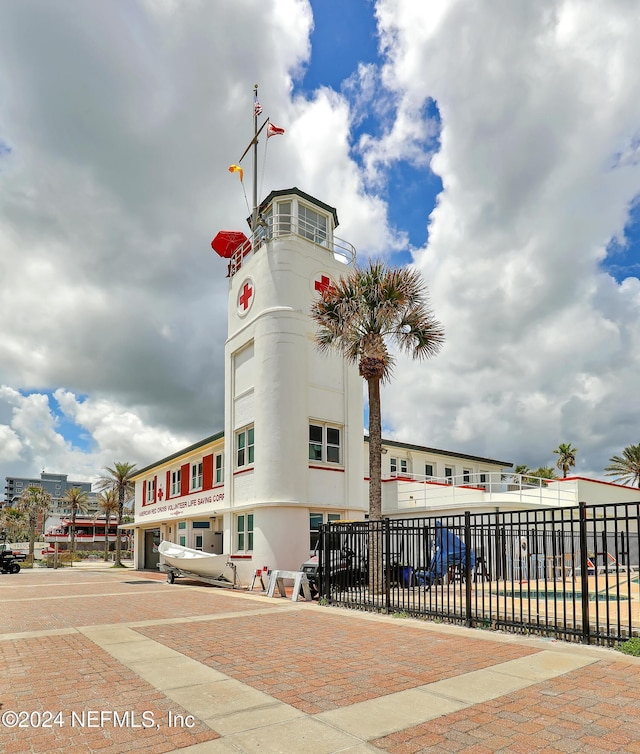 view of building exterior with decorative driveway and fence