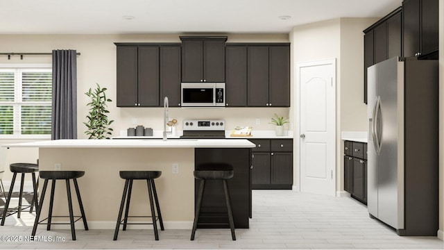 kitchen with a center island with sink, a kitchen breakfast bar, stainless steel fridge with ice dispenser, range, and white microwave