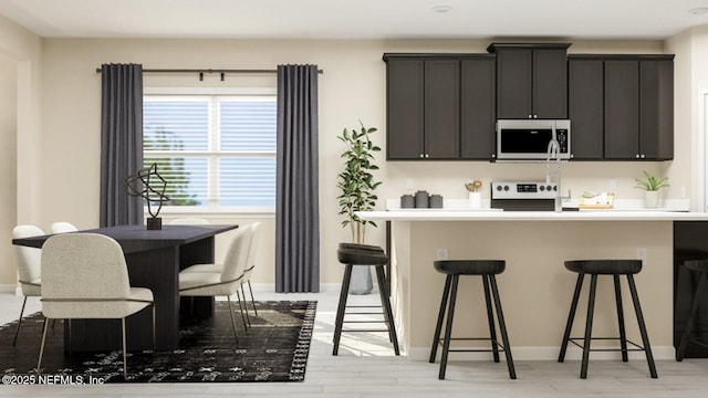 kitchen with stove, a breakfast bar area, light countertops, and light wood-style floors