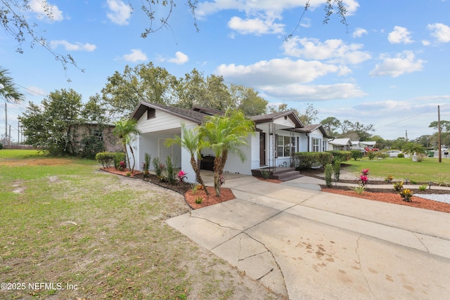 view of front of house with driveway, a front yard, and stucco siding