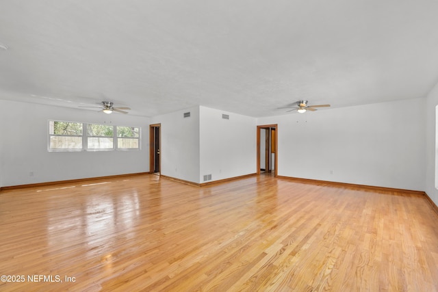 unfurnished room with a ceiling fan, light wood-type flooring, visible vents, and baseboards