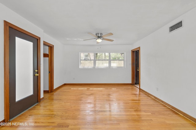 spare room with light wood-style flooring, a ceiling fan, visible vents, and baseboards