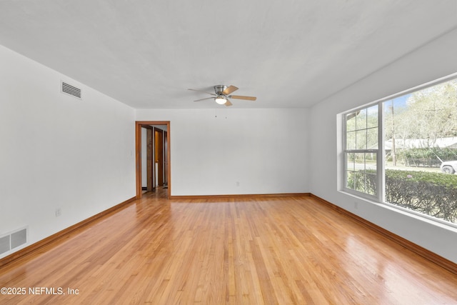 spare room with a ceiling fan, visible vents, light wood-style flooring, and baseboards