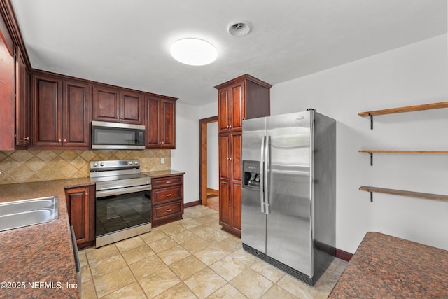 kitchen with visible vents, decorative backsplash, dark countertops, appliances with stainless steel finishes, and a sink