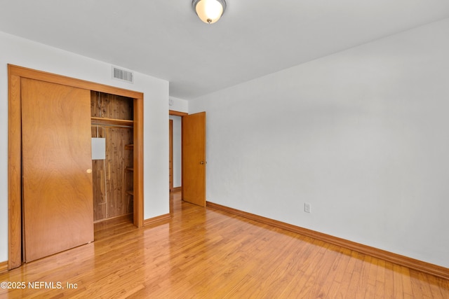 unfurnished bedroom featuring a closet, wood finished floors, visible vents, and baseboards