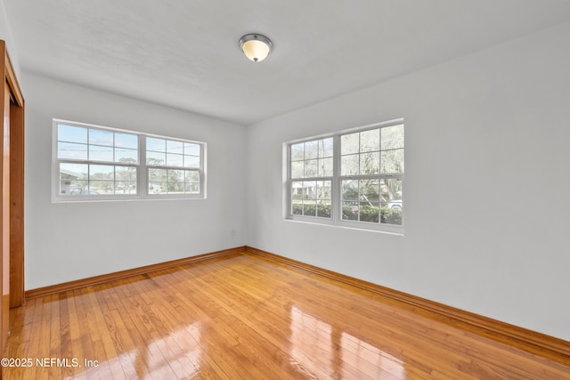 unfurnished room featuring plenty of natural light, light wood-style flooring, and baseboards