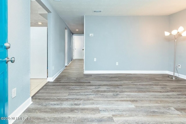 unfurnished room with wood finished floors, visible vents, and baseboards