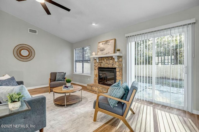 living room featuring lofted ceiling, visible vents, a fireplace, and wood finished floors