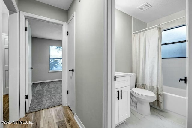 bathroom with toilet, vanity, visible vents, baseboards, and shower / tub combo with curtain