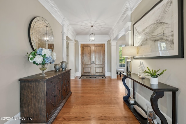 entryway featuring decorative columns, ornamental molding, light wood-style flooring, and baseboards