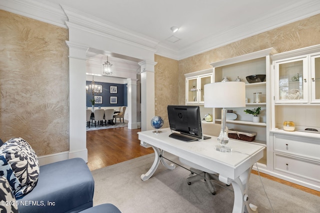 office space with crown molding, decorative columns, light wood-style flooring, a chandelier, and wallpapered walls