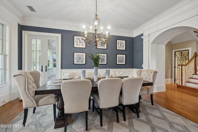 dining room with stairs, arched walkways, french doors, and wood finished floors