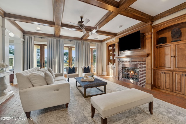 living room with french doors, beam ceiling, a brick fireplace, and a wealth of natural light