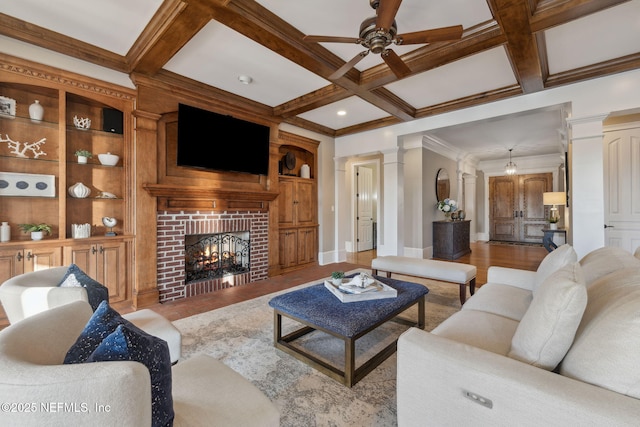 living room with a brick fireplace, decorative columns, coffered ceiling, and beam ceiling