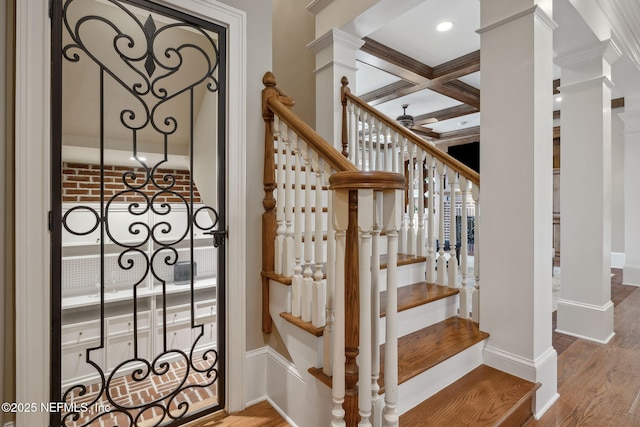 staircase with beam ceiling, ornate columns, wood finished floors, coffered ceiling, and baseboards