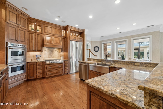 kitchen featuring stainless steel appliances, light wood-type flooring, a sink, and brown cabinets