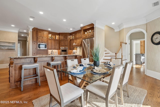 dining area featuring arched walkways, light wood-style flooring, visible vents, and recessed lighting