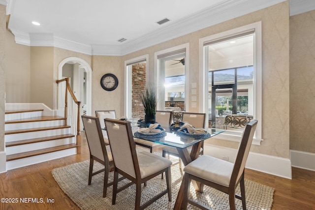 dining space with arched walkways, visible vents, stairway, and wood finished floors