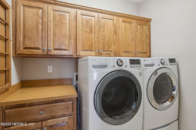 clothes washing area featuring cabinet space and washer and clothes dryer