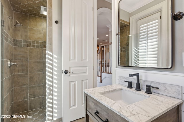 full bathroom featuring crown molding, a tile shower, and vanity