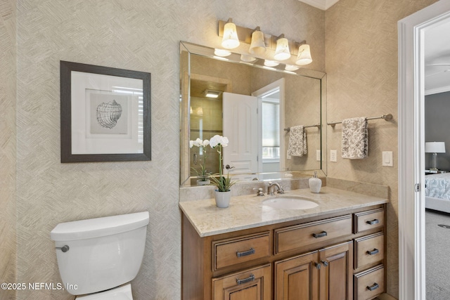 ensuite bathroom with toilet, wallpapered walls, ensuite bathroom, and vanity