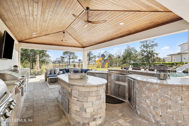 view of patio featuring a gazebo, an outdoor kitchen, a ceiling fan, a sink, and fence