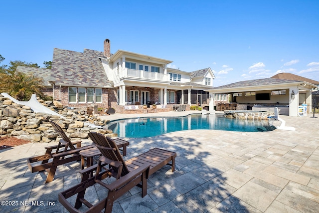 view of pool featuring exterior kitchen, a pool with connected hot tub, a patio, and outdoor dry bar