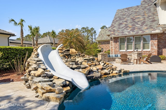 outdoor pool with a water slide and a patio area