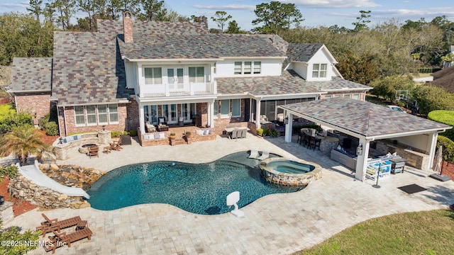 exterior space featuring an outdoor living space with a fire pit, outdoor dry bar, a water slide, a patio area, and a pool with connected hot tub