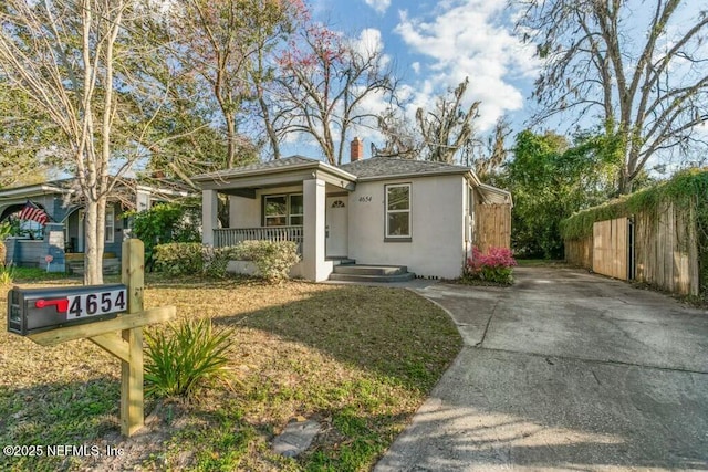 view of front of property with fence, a chimney, and stucco siding