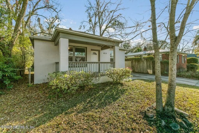 view of front of property with covered porch, fence, and stucco siding