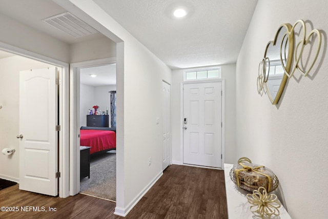 foyer featuring baseboards, visible vents, and dark wood-type flooring