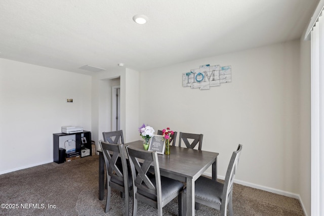 dining area featuring dark carpet and baseboards