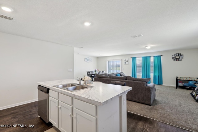 kitchen featuring light countertops, visible vents, open floor plan, a sink, and dishwasher