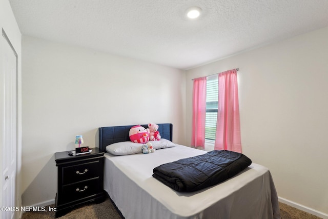 bedroom featuring baseboards, dark colored carpet, and a textured ceiling