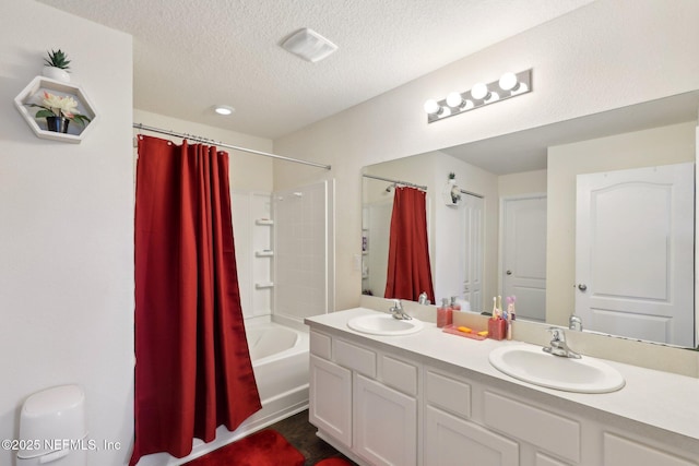 full bath with double vanity, shower / tub combo, a textured ceiling, and a sink