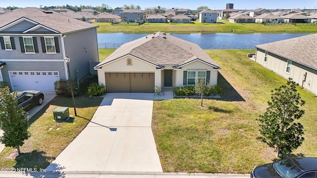 traditional-style house with an attached garage, a water view, driveway, a residential view, and a front yard