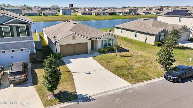 view of front facade featuring concrete driveway, a water view, a front yard, a garage, and a residential view