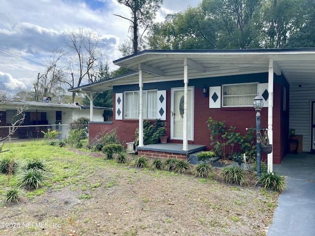 view of front of property featuring driveway, fence, an attached carport, and brick siding