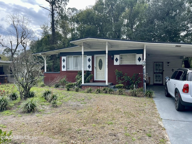 view of front facade with driveway, fence, a carport, and brick siding