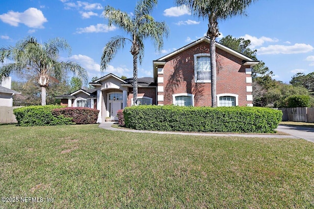 traditional-style home with a front yard, fence, and brick siding