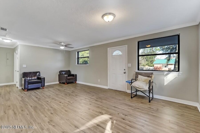 sitting room with ornamental molding, wood finished floors, a ceiling fan, and baseboards