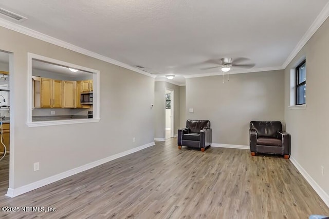 sitting room featuring visible vents, baseboards, a ceiling fan, light wood-style flooring, and ornamental molding