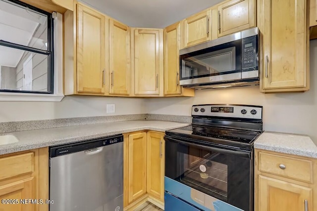 kitchen with stainless steel appliances, light brown cabinetry, and light countertops