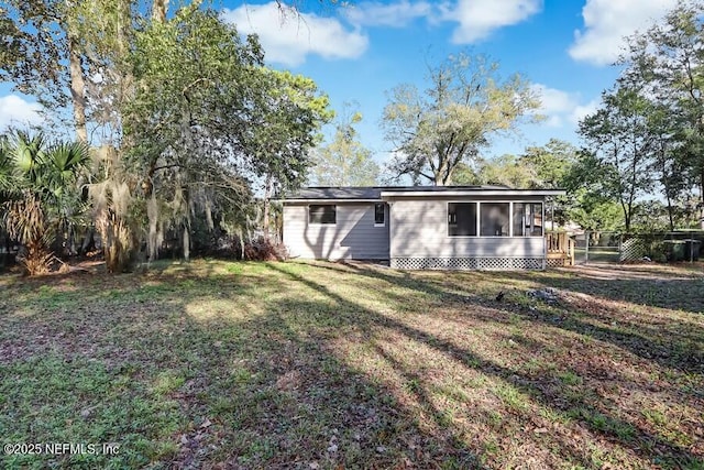 rear view of house featuring a lawn and a sunroom