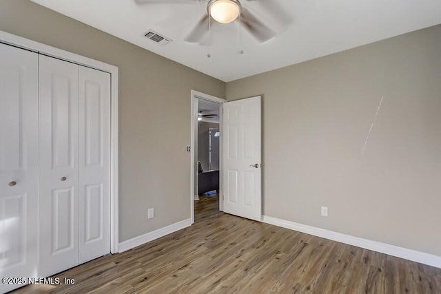 unfurnished bedroom featuring a closet, wood finished floors, visible vents, and baseboards