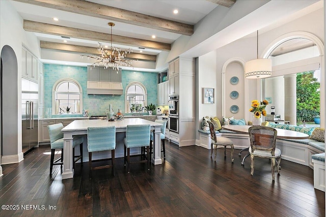 kitchen with a breakfast bar area, light countertops, dark wood-style floors, tasteful backsplash, and breakfast area