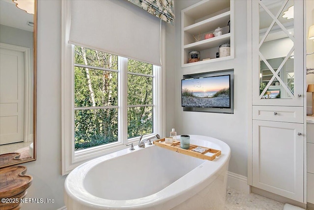 full bathroom featuring a freestanding tub and a wealth of natural light